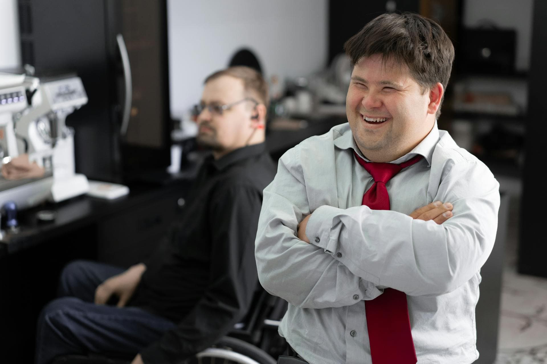 A worker with a disability laughs at a joke in the office.