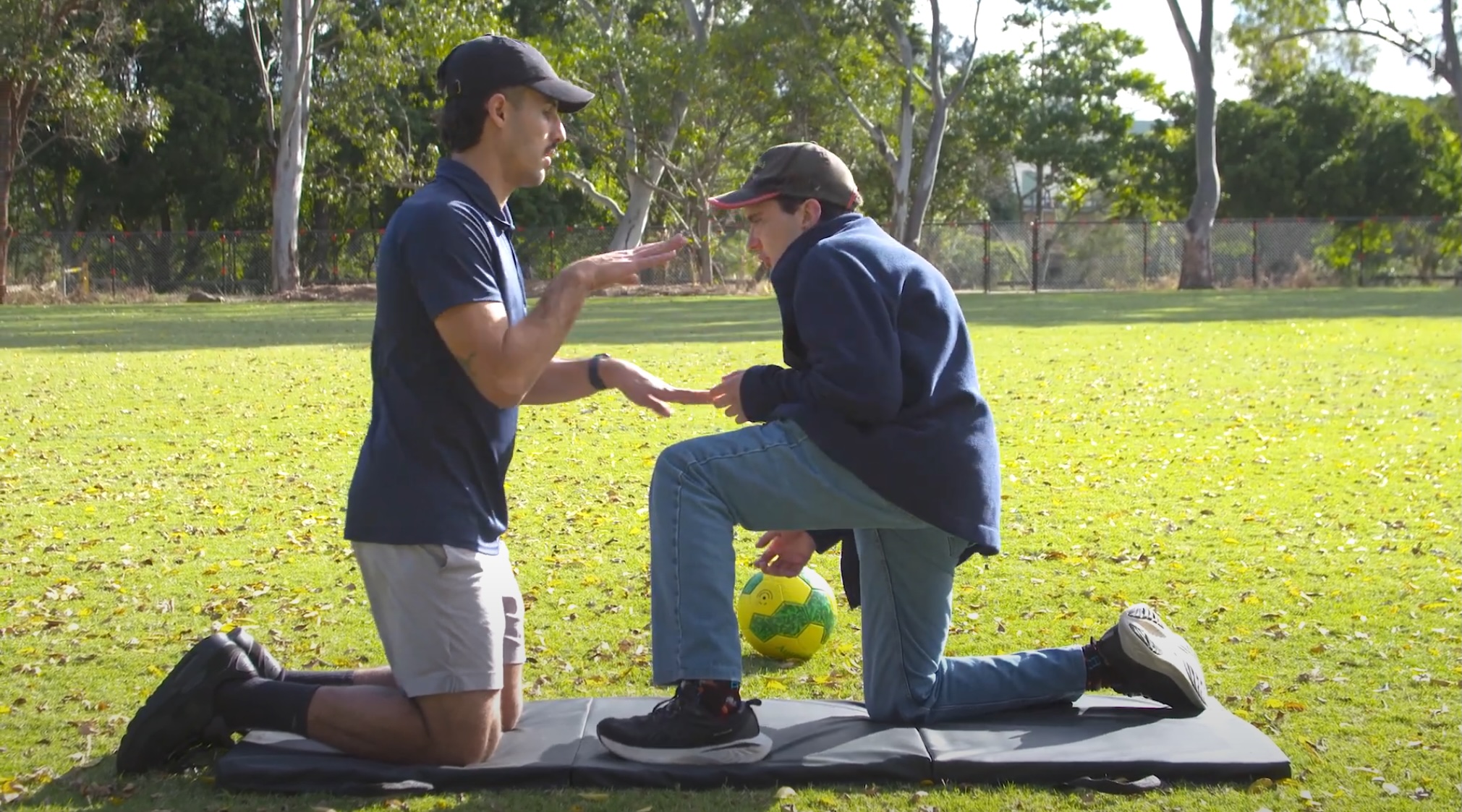 A support practitioner kneeling on the ground while person with disabilities is his knee in front.